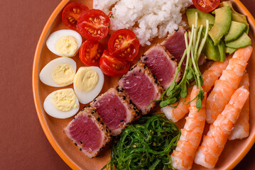 Seafood bowl, tuna tataki fillet slices with rice, oranges, tomatoes and sauce. Tuna bowl