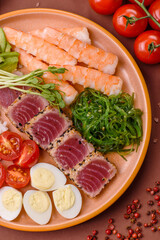 Seafood bowl, tuna tataki fillet slices with rice, oranges, tomatoes and sauce. Tuna bowl