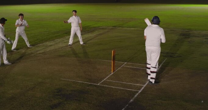 Asian cricket teammates bowling at ground, batsman missing shot, fielder catching ball, copy space