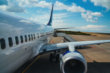 Airplane at an airport, ready for takeoff, with modern terminals, runways, and aviation activity in the background.