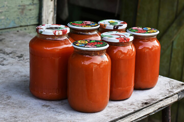 Tomato juice in glass jars on the table. Group glass of homemade juice, local farmer s market. The concept of farming and homestead agriculture.
