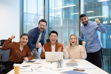 An enthusiastic team of diverse coworkers cheerfully celebrates success during a collaborative session in office setting. They exhibit teamwork, happiness, and achievement in professional workplace.