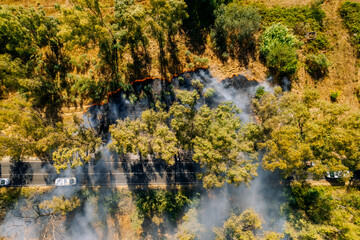 Aerial view of wildfire near road with smoke and flames