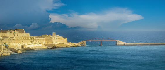 View of the western tip of the Grand Harbor entrance in Valletta, Malta. With the ruins of Fort. St. Elmo and the bridge connecting it to its breakwater prominent
