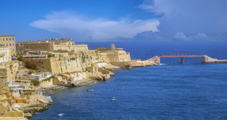 Obraz premium Picturesque fishing villages remaining on the cliffs of the city of Valletta, Malta. The ruins of Fort St. Elmo in the background