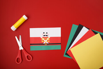 Holiday-themed DIY nutcracker craft materials with scissors, glue stick, paper shapes, cardboard tube, suitable for educational kits, craft blogs, hobby retailers, children holiday programs.