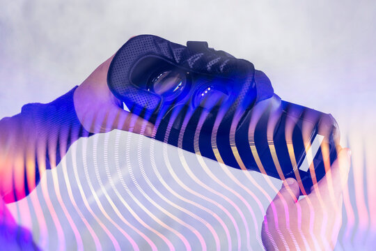 Close-up of hands holding virtual reality goggles with overlay of futuristic glowing bokeh lights. Concept of VR-technologies in investment analytics, digital innovation.