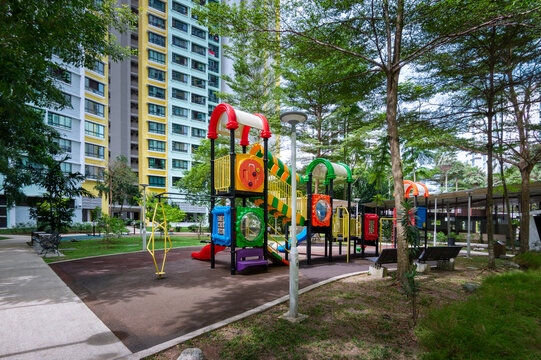 A garden path, rest area, and playground in a green landscape within an HDB estate, Singapore. Shaded by trees, the path and playground invite residents to enjoy a peaceful stroll in the landscape,
