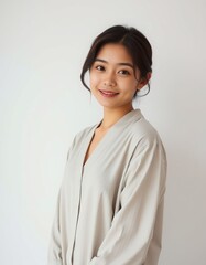 Portrait of a young asian woman smiling in a light colored button down shirt against white