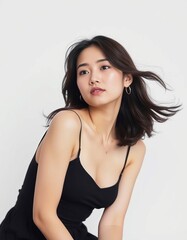 Portrait of a young woman with dark hair wearing a black dress against white background