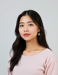 Fototapeta premium Portrait of a young asian woman with long dark hair wearing a pink top and gold earrings