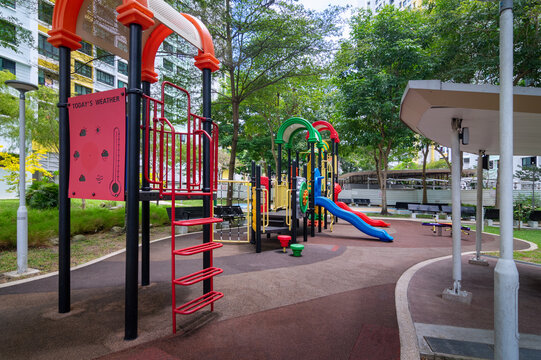 A garden path, rest area, and playground in a green landscape within an HDB estate, Singapore. Shaded by trees, the path and playground invite residents to enjoy a peaceful stroll in the landscape,
