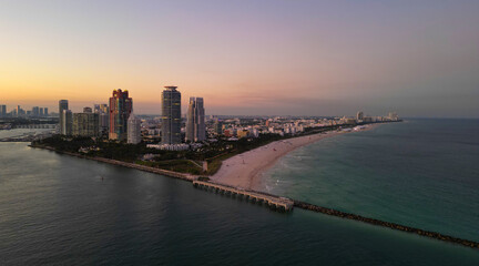 Fototapeta premium Miami Beach sunset aerial view. Downtown Miami skyline at dusk. South Beach neon lights at night. Tropical Miami waterfront panorama. Ocean Drive Art Deco buildings. Aerial view of Miami coastline.