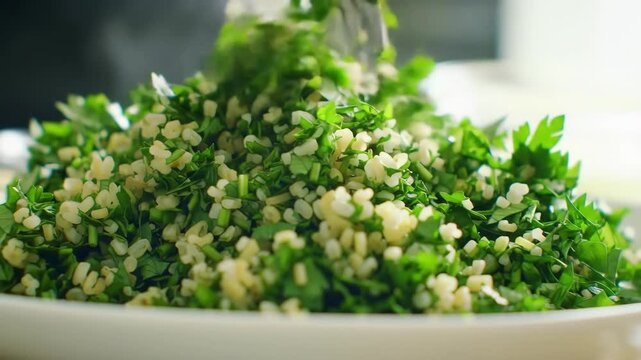 Close-up of Tabbouleh Preparation: Fresh Parsley and Bulgur Wheat Being Mixed on a White Plate for a Healthy and Delicious Mediterranean Salad