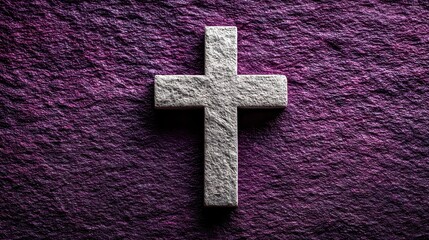 Stone cross resting on dark purple textured background offering concepts of Christianity and faith