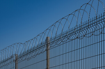 Razor wire. Metal wire fence. Blue sky background.
