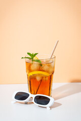 Summer iced cocktail drink with sunglasses and sunny shadows.