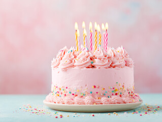 Pink birthday cake with candles on pink background.