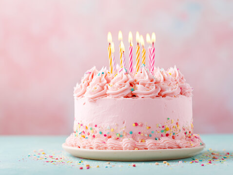 Pink birthday cake with candles on pink background.