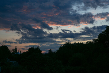 The vibrant colors of a dramatic sunset paint the sky over a building.