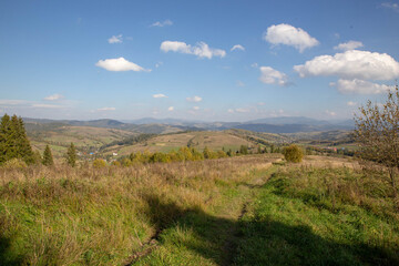 This beautiful landscape showcases a vast field of hills under a clear blue sky with clouds.