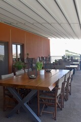 Outdoor patio wooden dining table and chairs on a balcony in Crete Greece; minimally decorated with candle lanterns and greenery plants