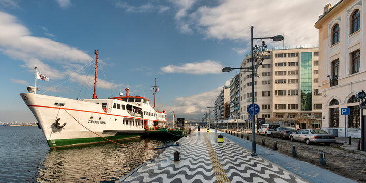Izmir, Turkey - April 6, 2025:ZUBEYDE HANIM ferry docked at Kordon promenade. Waterfront view with buildings and wavy pavement under a blue sky