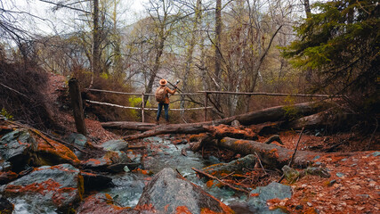 Traveler with camera and backpack exploring forest creek in Altai. Concept travel trip tour for photographer
