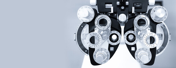 Precision optometry equipment for eye exams against light gray background, banner copy space