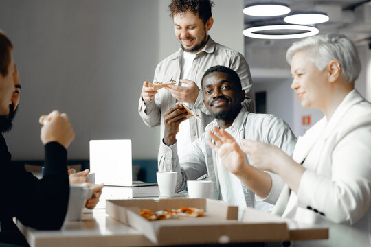 Diverse Corporate Team Enjoying a Casual Office Lunch with Pizza and Coffee