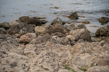 Rocky shoreline with clear water and space for text. Natural coastal landscape with stones and gentle waves. Ideal for nature and travel concepts.