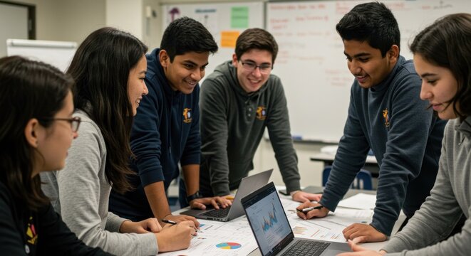 Students collaborate around a table with laptops and charts - Powered by Adobe
