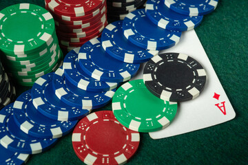 A close-up of various colored poker chips stacked along with an ace card on a green felt table, capturing the excitement of a night of card games at a casino