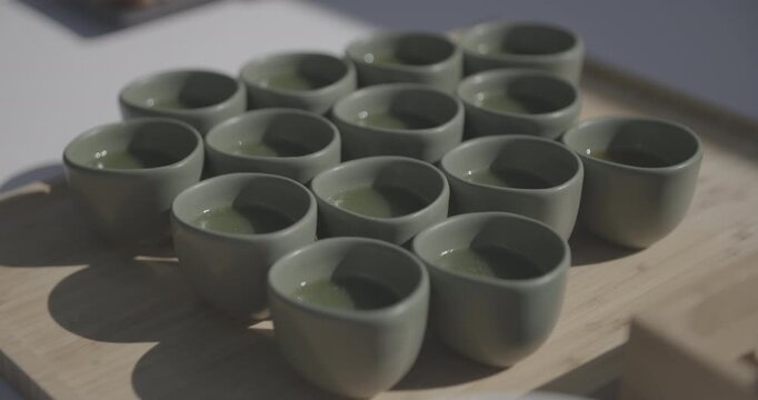 Ensemble de petits bols en c&eacute;ramique de couleur verte contenant des jus frais de l&eacute;gumes assaisonn&eacute;s et pr&ecirc;t &agrave; &ecirc;tre bu par les invit&eacute;s pendant une r&eacute;ception
