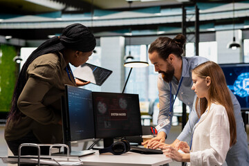 Young engineer in office requests help from IT experts detecting and blocking hacker intrusion. Female programmer assisted by staff members coordinating incident response for network attack