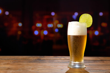 Refreshing beer with a slice of lemon on a wooden table in a bar