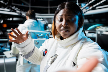 Astronaut doing video briefing with Earth based scientists team using selfie smartphone camera in orbit station. African american woman in starship presents current mission status during videocall
