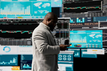 Black professional administrator examining digital dashboard with finance graphs, working on strategic planning with infographics on gadget. Corporate economy management and analysis.