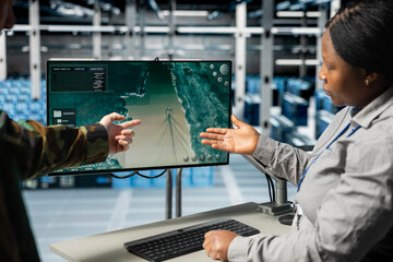 Team of military engineers in data center tracking satellite coordinates using monitor interface. Teamworking server room coworkers analyzing reconnaissance data through satellite imaging systems
