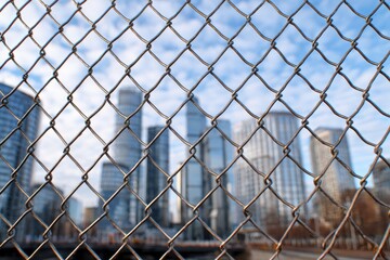 Chain link mesh in front of city towers