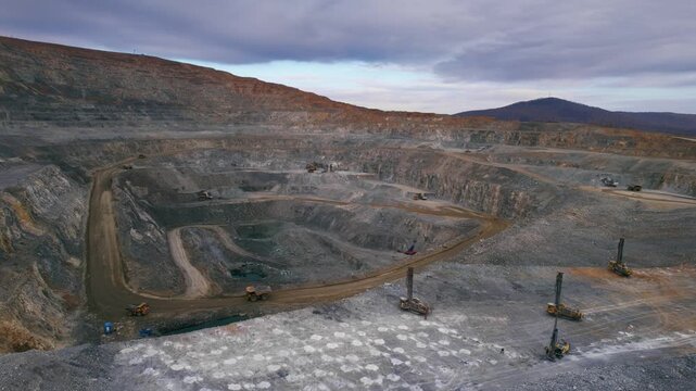 Drilling rigs drill holes to install explosives to blast rock mass in open pit mine. Aerial view Mining industry gold ore with big dump truck.