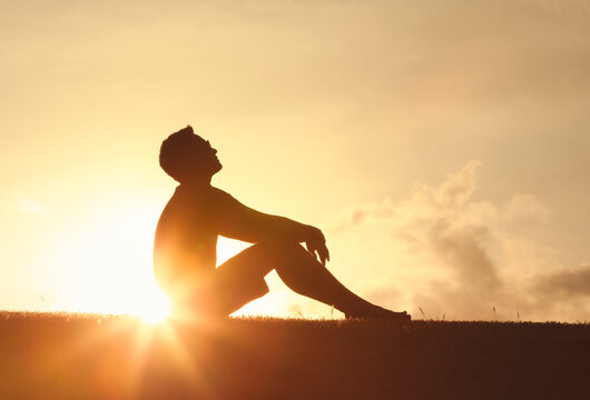 Young man looking up at the morning sun light sky finding happiness, peace and hope in nature - Powered by Adobe