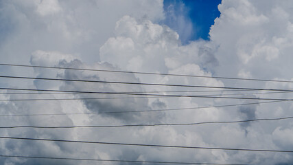 Dramatic view cumulus clouds filling the sky with power lines cutting across the scene striking contrast between natural and man-made elements. 