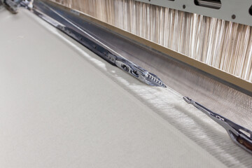 Rapier loom gripper at reed weaving wool fabric in a modern textile mill