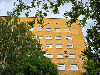 Brick building surrounded by greenery on a cloudy day in an urban setting