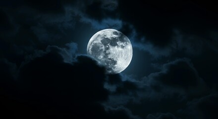 Full moon in dramatic night sky with dark storm clouds creating moody atmospheric celestial photography
