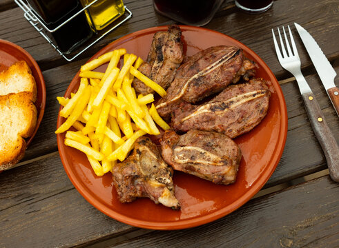 Spanish traditional dish - baked pork cheeks with french fries for dinner close-up