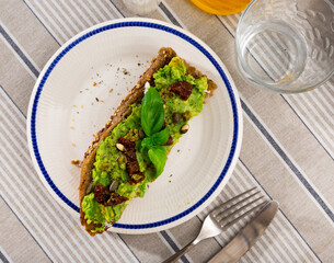 Delicious toast with cheese and guacamole, dried tomatoes and seeds served to table