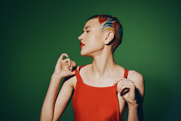 Woman with artistic short hairstyle and colorful hair dye wearing a red sleeveless top, posing...