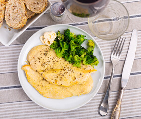 Stewed chicken fillet with spices and fresh broccoli on a white plate. Low-calorie protein lunch with vegetables